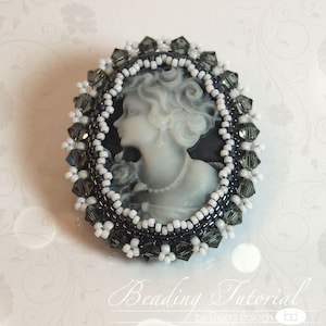 May include: A black and white cameo brooch with a beaded border. The beads are white and black with a few clear crystals. The cameo features a woman's profile.