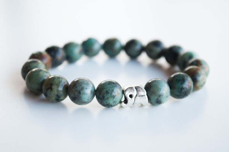 May include: A turquoise green beaded bracelet with a silver elephant charm.