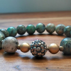 May include: A turquoise and gold beaded bracelet with a sparkly silver center bead.