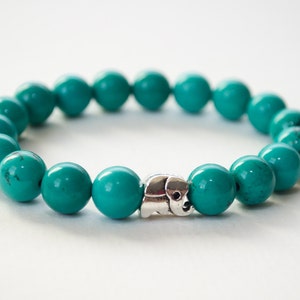 May include: A turquoise beaded bracelet with a silver elephant charm.