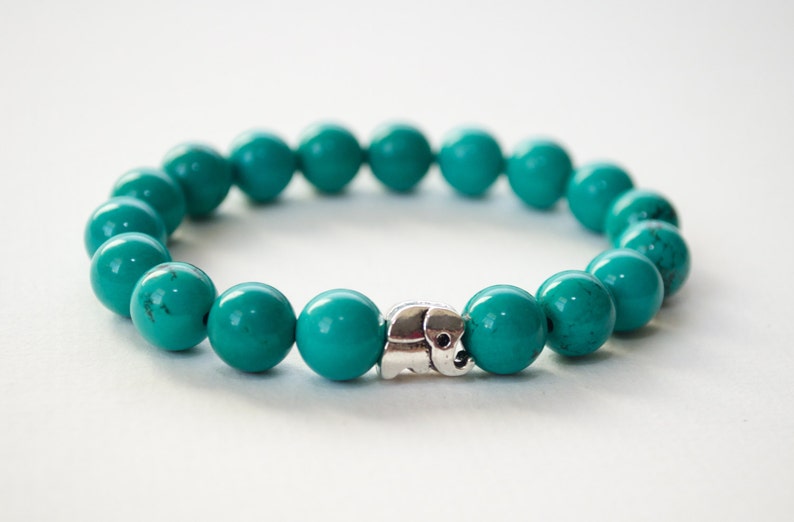 May include: A turquoise beaded bracelet with a silver elephant charm.