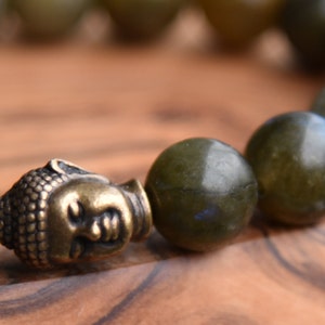 May include: A green labradorite gemstone bracelet with a gold-toned Buddha head charm.