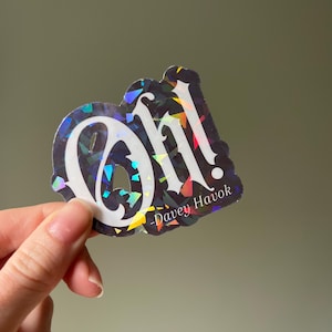 May include: A holographic sticker with the word "Oh!" in white gothic lettering. The sticker has a dark background with iridescent accents and the text "-Davey Havok" in a smaller font.