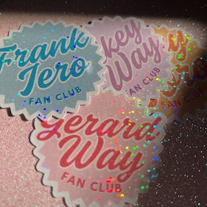 May include: A selection of colourful, scalloped-edge stickers with holographic detailing. Each sticker displays a different name in a stylized font, including "Frank Jero" and "Gerard Way," and the text "FAN CLUB". The stickers are set against a glittery pink background.