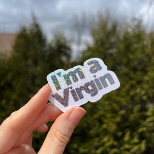 Könnte beinhalten: Ein weißer Aufkleber mit einem Regenbogen-Glitzer-Hintergrund und schwarzem Text, der "I'm a Virgin" lautet.
