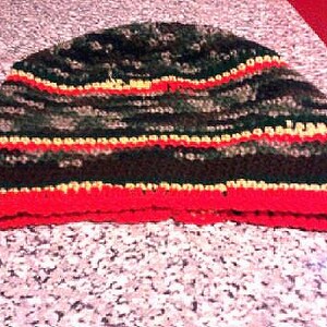 May include: A black, green, red, and yellow striped crocheted beanie hat.