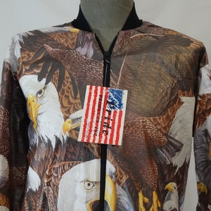May include: A brown, black, and white bomber jacket with a zipper closure and an all-over print of bald eagles. The jacket has a tag that reads "Pride Products Inc."