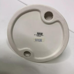Op de afbeelding: Witte keramische figuurbasis met een gat om op te hangen. De basis heeft de tekst "Schmid" en "The Walt Disney Company" erop gedrukt.