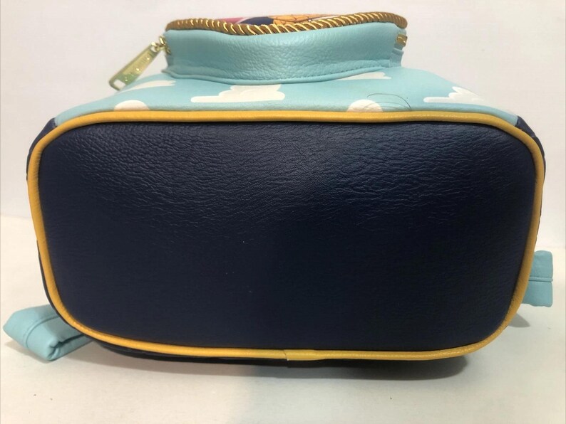May include: A backpack with a navy blue base, light blue top, and yellow trim. The top features a sky blue pattern with white clouds. The zipper is gold. The backpack has light blue straps.