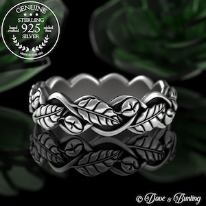 May include: A sterling silver ring with a leaf design. The ring is crafted with a leaf pattern around the band. The ring is nickel free and made in the USA. The image also includes the text "GENUINE STERLING 925 SILVER" and "Dove & Bunting."