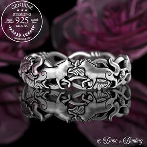 May include: Sterling silver ring featuring two wolves intertwined with leaves and acorns. The ring is made in the USA and is nickel free.