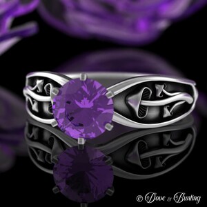 May include: A silver ring with a purple gemstone and a mushroom design. The ring is set on a black background.