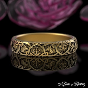 May include: A gold wedding band with an intricate floral design. The band is made of a smooth, polished metal and features a repeating pattern of flowers and leaves.