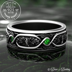 May include: Sterling silver ring featuring a tree of life design and two green gemstones. The ring is handcrafted and nickel-free. "GENUINE STERLING 925 SILVER MADE IN THE USA" is printed on the ring.