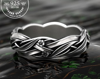 Puede incluir: Un anillo de plata de ley con un diseño trenzado y pequeños detalles florales. El anillo está marcado con "925 Silver" y "Made in the USA". El anillo es libre de níquel y hecho a mano.