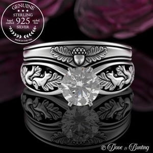 以下が含まれることがあります： 大きな透明な宝石がセットされたスターリングシルバーのリング。リングには、リスとドングリの詳細なデザインが施されています。