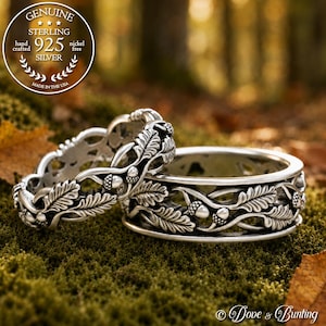 May include: Two sterling silver rings featuring an intricate, raised relief design of oak leaves and small acorns. The metal has an oxidized finish to highlight the botanical details. A circular stamp in the corner reads Genuine Sterling 925.