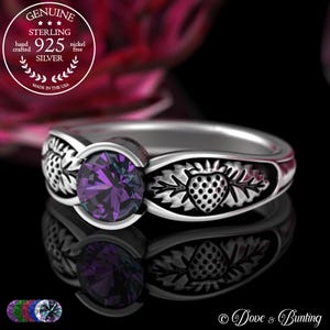 Puede incluir: Un anillo de plata de ley con una gran piedra preciosa púrpura facetada. El anillo presenta un diseño de fresa en la banda y está estampado con "925 SILVER" y "MADE IN THE USA". El anillo es libre de níquel y está hecho a mano.