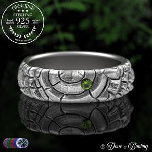 May include: A sterling silver ring with a textured, patterned design and a green gemstone. The ring is hand-crafted and nickel-free. The image includes the text "GENUINE STERLING 925 SILVER MADE IN THE USA".