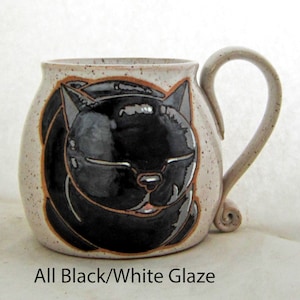 Pode incluir: Uma caneca de cer&acirc;mica com um desenho de gato preto. A caneca tem um exterior bege salpicado com uma ilustra&ccedil;&atilde;o de gato preto. A al&ccedil;a &eacute; bege e tem um design enrolado na base. O texto "All Black/White Glaze" est&aacute; na parte inferior.