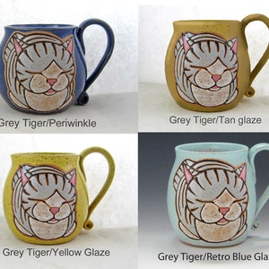 Pode incluir: Quatro canecas de cer&acirc;mica com desenhos de gatos cinzentos e rosa. As canecas s&atilde;o esmaltadas em azul-p&aacute;lido, bege, amarelo e azul retr&ocirc;. Cada caneca tem uma al&ccedil;a curva. O texto nas canecas diz "Grey Tiger" e a cor da esmalta&ccedil;&atilde;o.