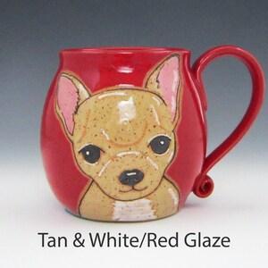 Puede incluir: Una taza de cer&aacute;mica roja con una ilustraci&oacute;n de chihuahua marr&oacute;n y blanco. La taza tiene un cuerpo redondeado y un asa curva.