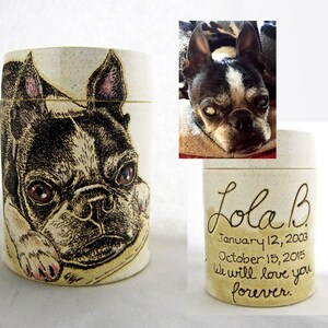 K&ouml;nnte beinhalten: Eine wei&szlig;e Keramikurne mit einer Schwarzwei&szlig;illustration eines Boston Terrier Hundes. Die Urne tr&auml;gt den Text "Lola B" sowie die Daten "12. Januar 2003" und "15. Oktober 2015". Der Text "Wir werden dich f&uuml;r immer lieben." ist ebenfalls auf der Urne geschrieben.