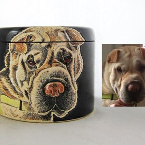 K&ouml;nnte beinhalten: Eine schwarze Keramikdose mit einem handgemalten Bild eines Shar-Pei-Hundes. Der Hund hat ein hellbraunes und schwarzes Fell und schaut direkt auf den Betrachter. Die Dose hat einen Deckel.