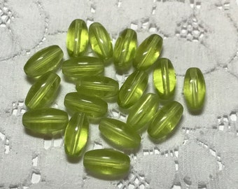 May include: A collection of 18 green glass beads with a translucent finish. The beads are oval shaped and have a striated pattern.