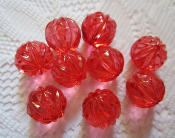 May include: A group of ten red, faceted, plastic beads with a ribbed design.