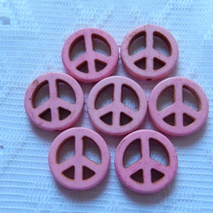 Può includere: Sette perline di legno rosa a forma di segno della pace. Le perline hanno un diametro di circa 2,5 cm.
