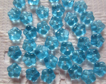 May include: A collection of light blue plastic flower-shaped beads. The beads have a hole in the center for stringing.