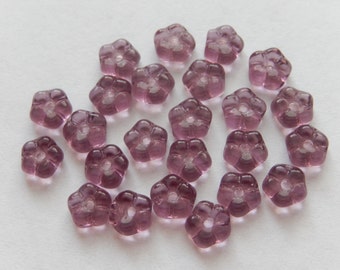May include: A group of 25 purple glass flower beads. The beads are translucent and have a slightly iridescent finish.