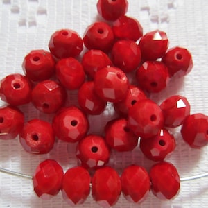 May include: A pile of bright red faceted glass beads. The beads are round and have a hole in the center. They are perfect for jewelry making or other craft projects.