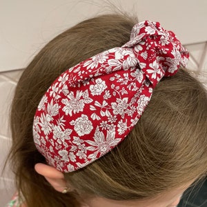 May include: A red and white floral patterned headband with a knotted design.