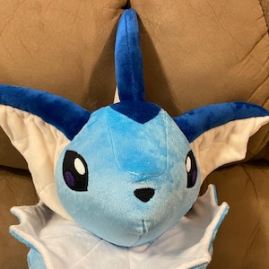 Puede incluir: Un juguete de peluche azul y blanco de un personaje de Pokemon con una aleta en la cabeza y orejas grandes.