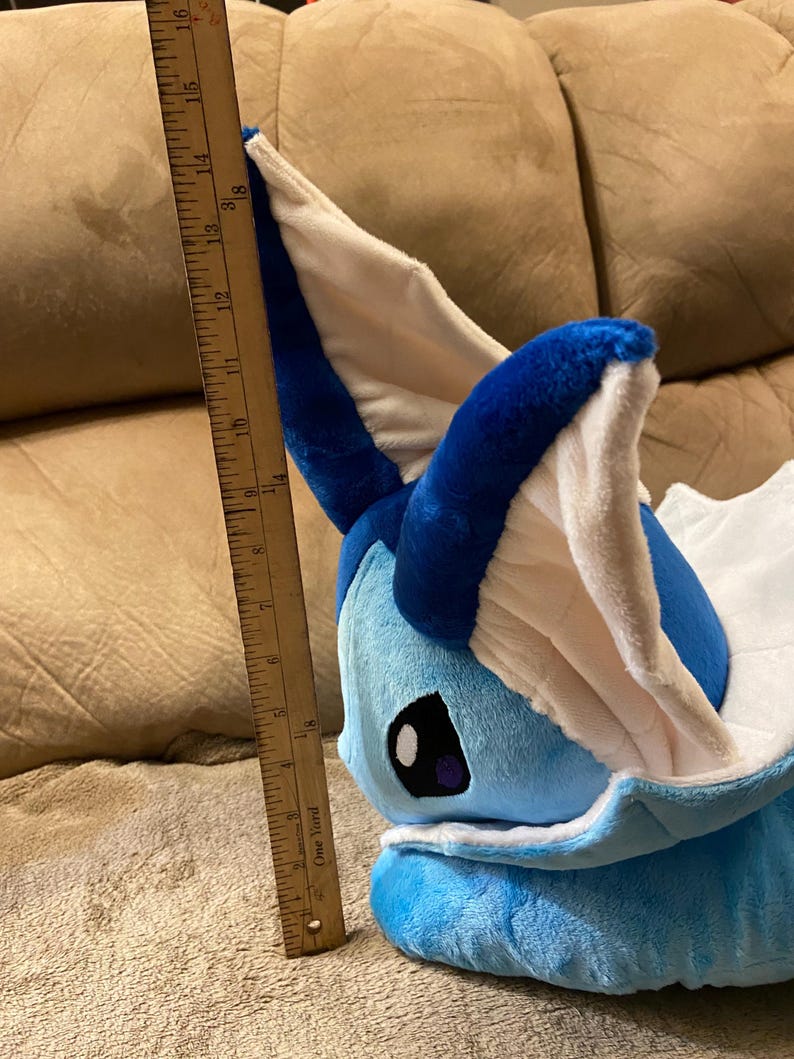 Puede incluir: Un juguete de peluche azul y blanco con forma de personaje Pokemon. El juguete mide aproximadamente 40 cm de alto y est&aacute; sentado en un sof&aacute; marr&oacute;n.