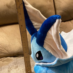 Puede incluir: Un juguete de peluche azul y blanco de un personaje Pok&eacute;mon, Glaceon, con una regla de 38 cm de largo a su lado.