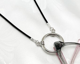 May include: Black leather eyeglass chain with silver metal clasps and a round ring. The chain is attached to a pair of glasses.