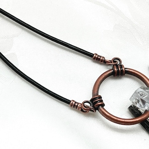 May include: A black leather eyeglass chain with copper wire accents. The chain has a circular copper wire loop at the center.