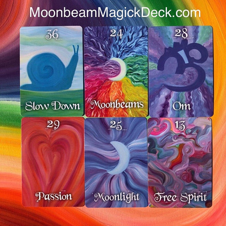 May include: A collection of six tarot cards from the Moonbeam Magick Deck. The cards feature colorful illustrations with themes including a blue snail, a crescent moon, and the word "Om". The cards also include the words "Slow Down", "Moonbeams", "Passion", "Moonlight", and "Free Spirit".