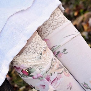 May include: White floral leggings with a lace trim and a pink button. The leggings are worn with a white skirt.