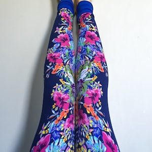 May include: A pair of navy blue leggings with a colorful floral print featuring pink, yellow, green, and blue flowers. The leggings have a blue waistband.