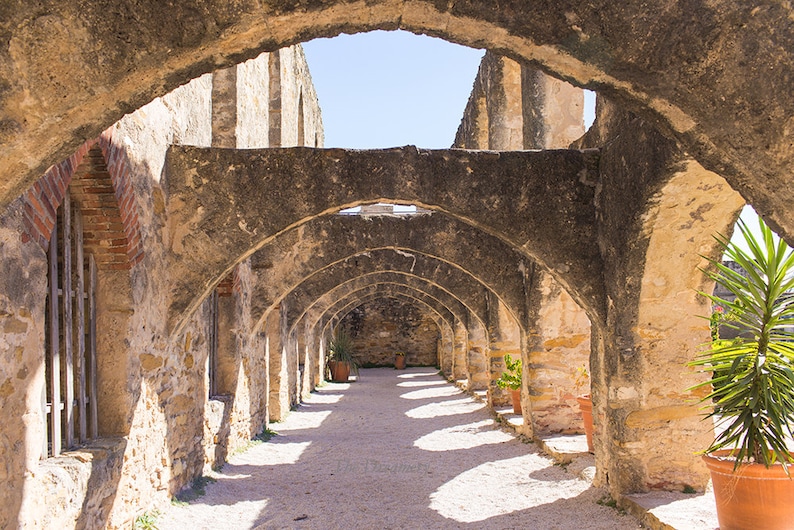 Puede incluir: Un largo y estrecho pasillo con una serie de arcos de piedra. Los arcos est&aacute;n hechos de piedra toscamente labrada y est&aacute;n sostenidos por pilares. El pasillo est&aacute; iluminado por la luz del sol que entra por la parte superior de los arcos. El suelo est&aacute; hecho de grava.
