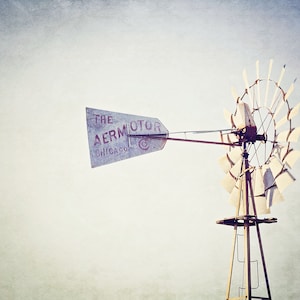 May include: A vintage windmill with a weathered wooden frame and white blades. The windmill has a sign that reads "The Aermotor Chicago".