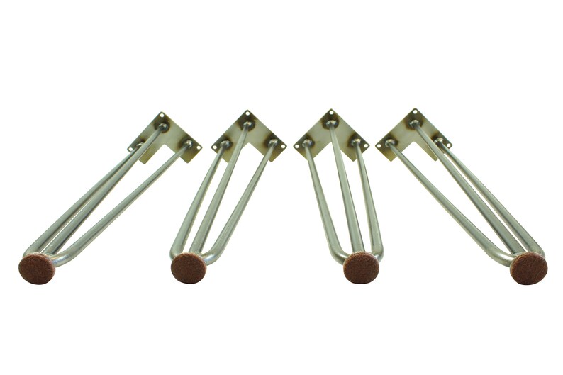 May include: Four silver metal hairpin table legs with brown felt pads on the bottom. The legs are designed to be attached to a table top.