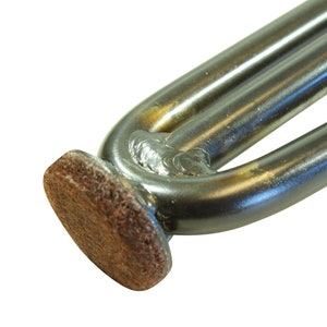 May include: Close-up of a metal furniture leg with a brown felt pad on the bottom. The leg is made of two metal tubes welded together.