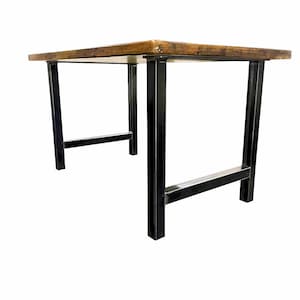 May include: A rectangular table featuring a thick, natural-toned wooden top with a visible grain and texture. The table is supported by four sturdy, black metal legs connected by horizontal support bars on each side, creating a stable frame.