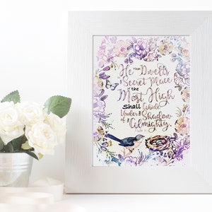 May include: A watercolor print with a floral wreath and a bird with a nest. The print features the text "He Dwells in the Secret Place of the Most High Shall Abide Under the Shadow of the Almighty."