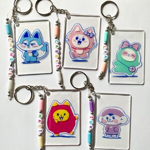 May include: Five clear acrylic keychains with colorful beaded charms. Each keychain features a different cartoon animal character. The charms spell out the names "Chun-gee", "Cabbit", "Lya", "Haitt", and "Tukk".